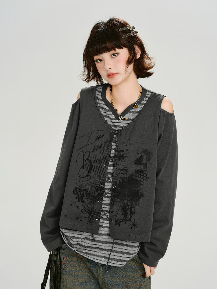 Model wearing a grey long-sleeve top with cold shoulder cutouts and a graphic print, layered over a striped t-shirt.