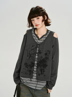 Model wearing a grey long-sleeve top with cold shoulder cutouts and a graphic print, layered over a striped t-shirt.