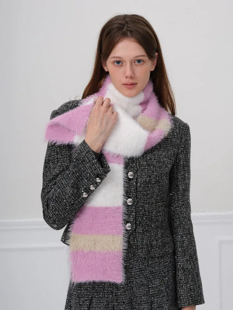 Woman adjusting a pink, white, and beige striped fuzzy scarf.