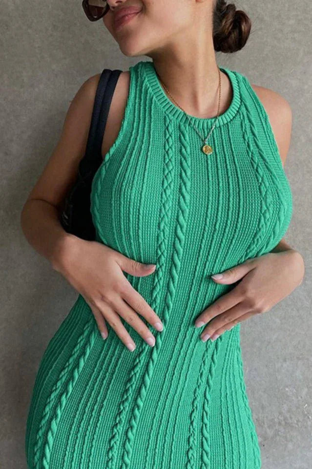 Close-up of a woman wearing a green sleeveless cable knit midi dress, hands on her stomach.