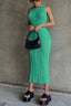 Woman wearing a green sleeveless cable knit midi dress, black platform sandals, and a black handbag.