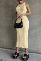 Woman wearing a cream sleeveless cable knit midi dress, black platform sandals, and a black handbag.