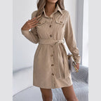 Woman wearing a tan corduroy shirt dress with a belted waist and collared neckline.