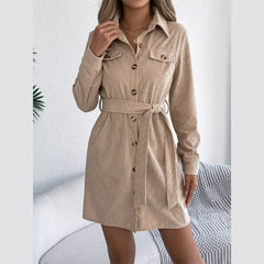 Close-up of a woman's upper body wearing a tan corduroy shirt dress, highlighting the collar and chest pockets.
