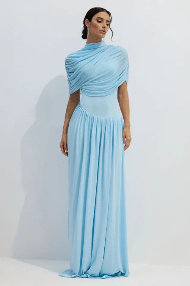 Full-length view of a woman in a light blue formal gown, showcasing the draped shoulder detail and pleated skirt. Secondary image
