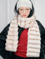 Model wearing a cream and brown striped faux fur scarf and a white ribbed headband.