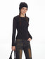 Model smiling and wearing a black ribbed knit top and distressed flared jeans with fur trim cuffs.