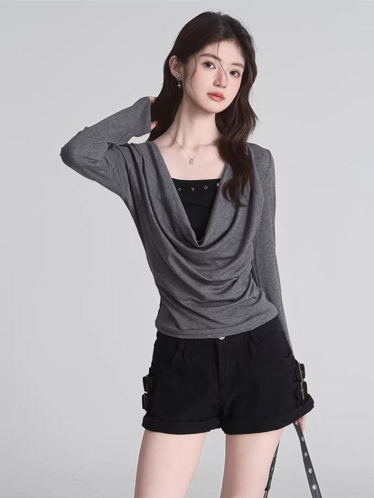 Woman wearing a grey draped long-sleeve top over a black camisole, paired with black shorts.