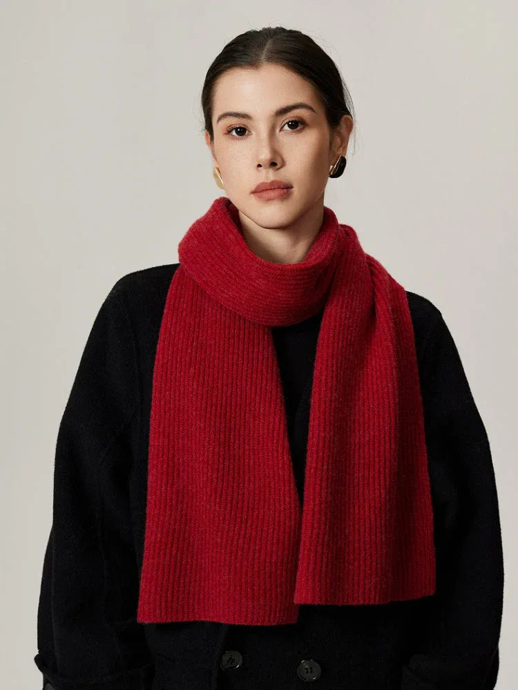 Woman wearing a red ribbed knit scarf over a black sweater.