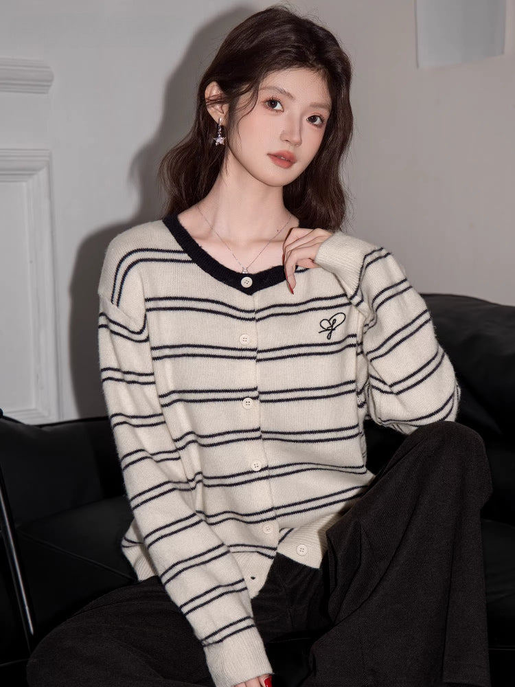 Woman posing while wearing a cream and black striped button-up knit cardigan.