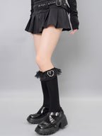 View of the lower half of a model's legs showcasing black knee-high socks with lace accents and platform shoes.