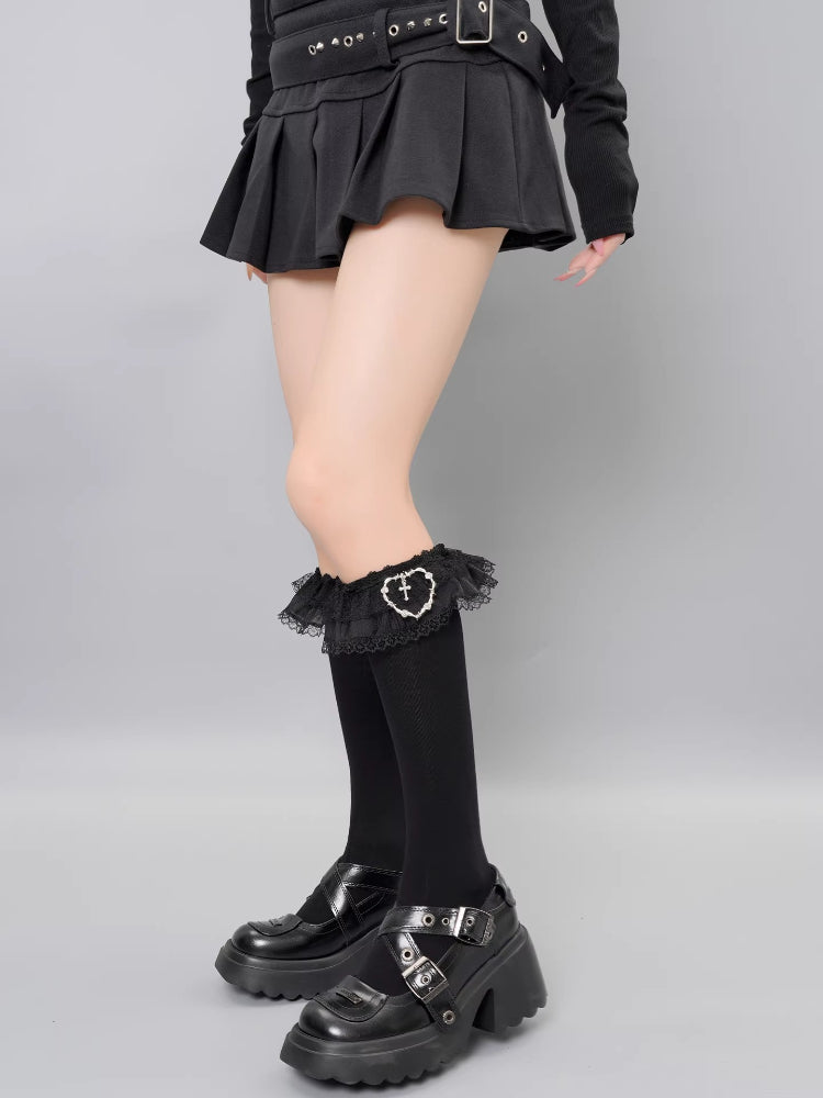 View of the lower half of a model's legs showcasing black knee-high socks with lace accents and platform shoes.