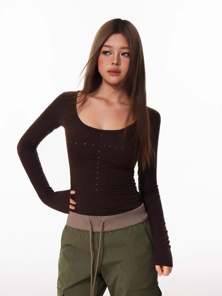 Woman in a brown long-sleeved top and olive green cargo pants posing with hand on hip.