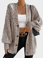Model wearing a brown and white striped oversized knit cardigan with a white crop top and black jeans