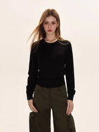 Woman wearing a black crew neck knit sweater with a ribbed hem, paired with olive green cargo pants.