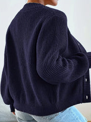 Back view of a woman wearing a navy blue oversized knit cardigan, showing the ribbed texture and balloon sleeves.