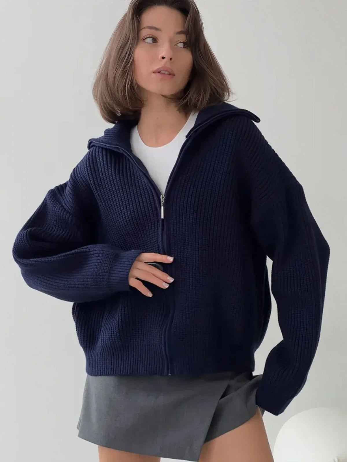 Close-up of a woman wearing a navy blue zip-up cardigan.