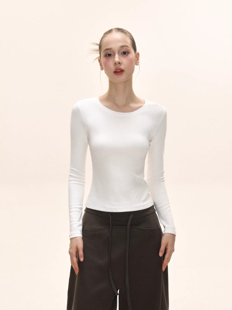 Front view of a model wearing a white long-sleeve ribbed knit top.