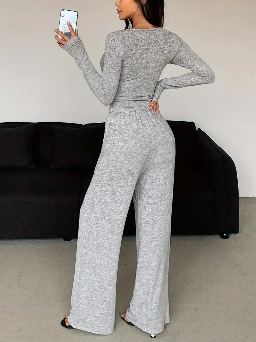 back view of a woman wearing a grey knit loungewear set with a long sleeve top and wide leg pants