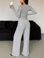 back view of a woman wearing a grey knit loungewear set with a long sleeve top and wide leg pants