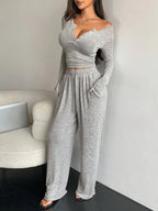 full shot of a woman in a grey knit loungewear set, standing next to a chair