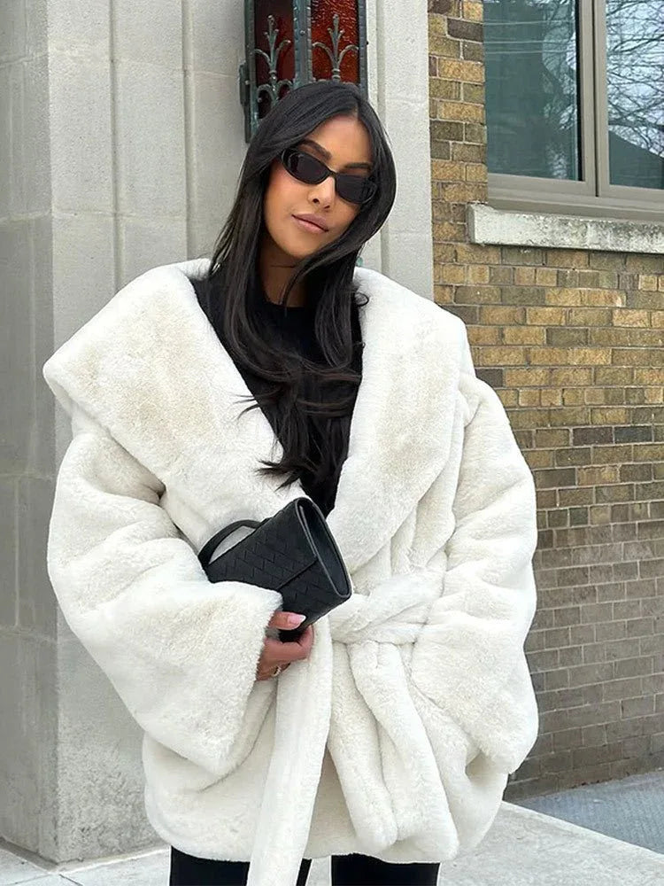 Woman wearing a white faux fur robe coat with a black clutch