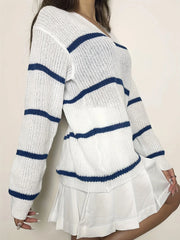 Woman wearing a white and blue striped v-neck sweater and a white pleated skirt, posing with arms crossed.