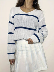 Close-up of a woman wearing a white and blue striped v-neck sweater and a white pleated skirt.