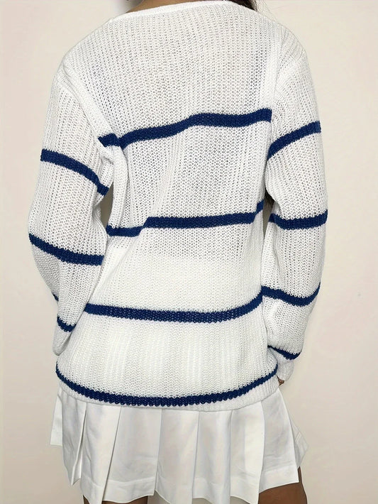 Back view of a woman wearing a white and blue striped v-neck sweater with a white pleated skirt.