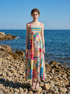 Woman wearing a colorful printed maxi dress on a rocky beach with the ocean in the background