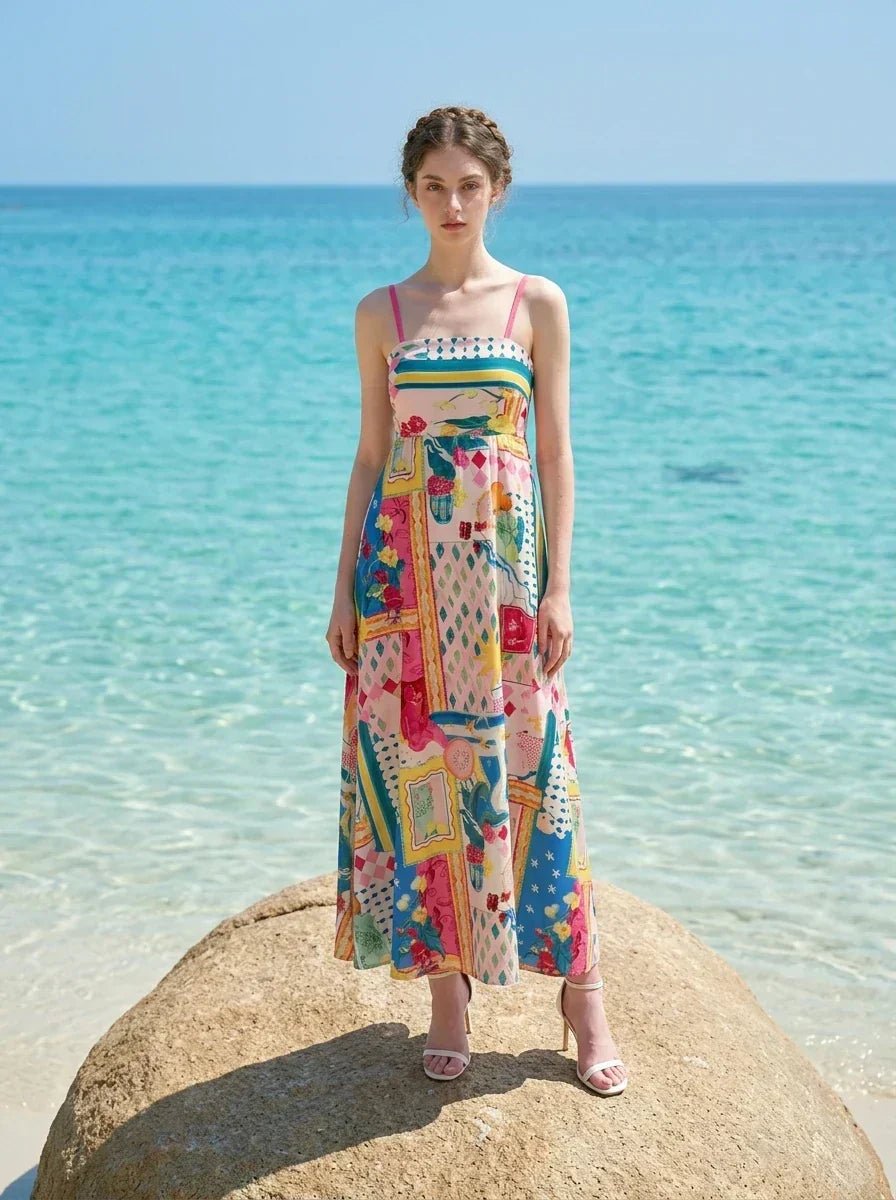 Woman wearing a colorful printed maxi dress standing on a rock with turquoise water in the background