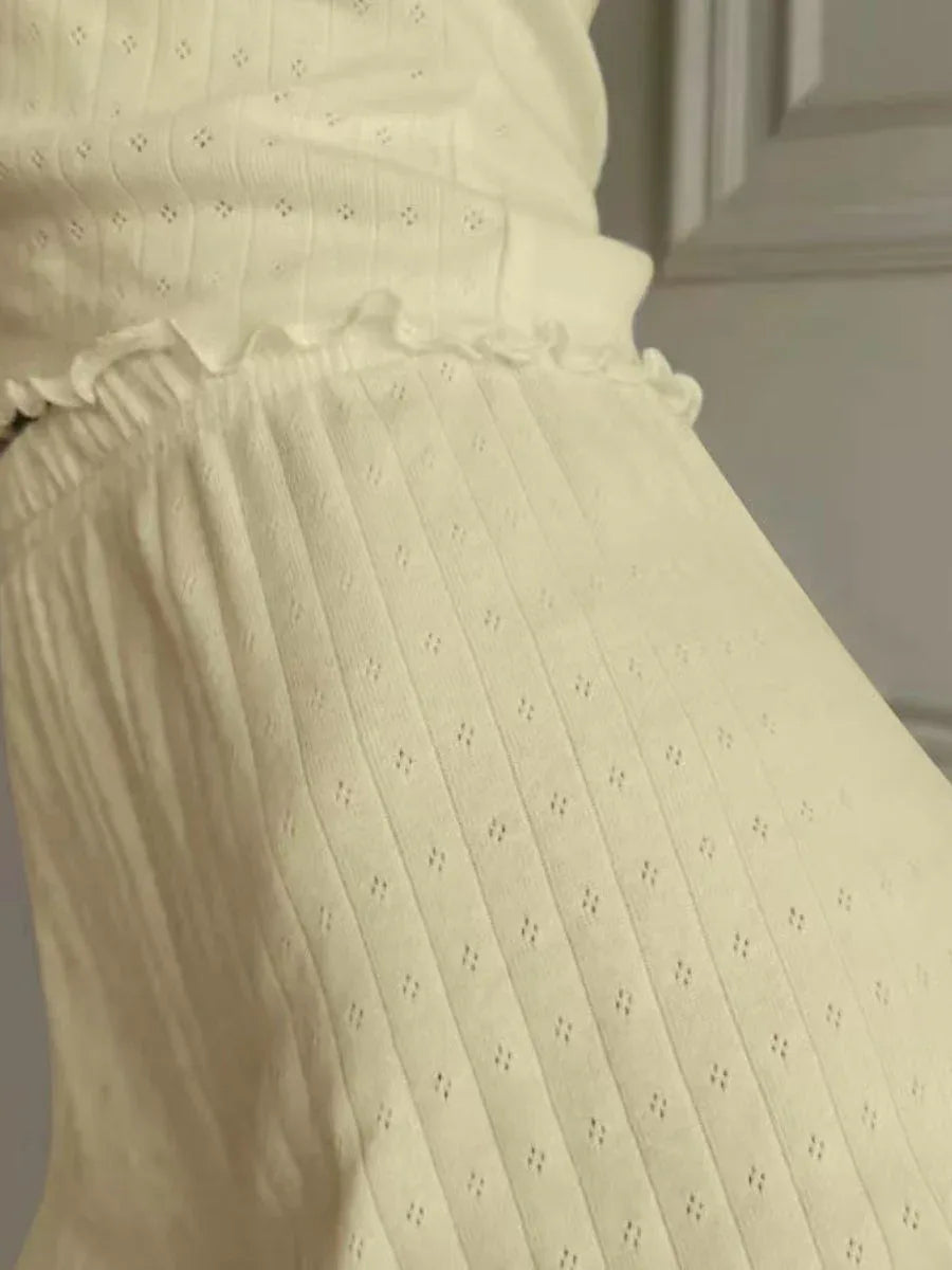 Close-up of the scalloped waistband and ribbed texture of the shorts in a cream color.