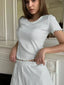 Woman wearing a white ribbed t-shirt with scalloped trim and matching white ribbed shorts with scalloped trim.