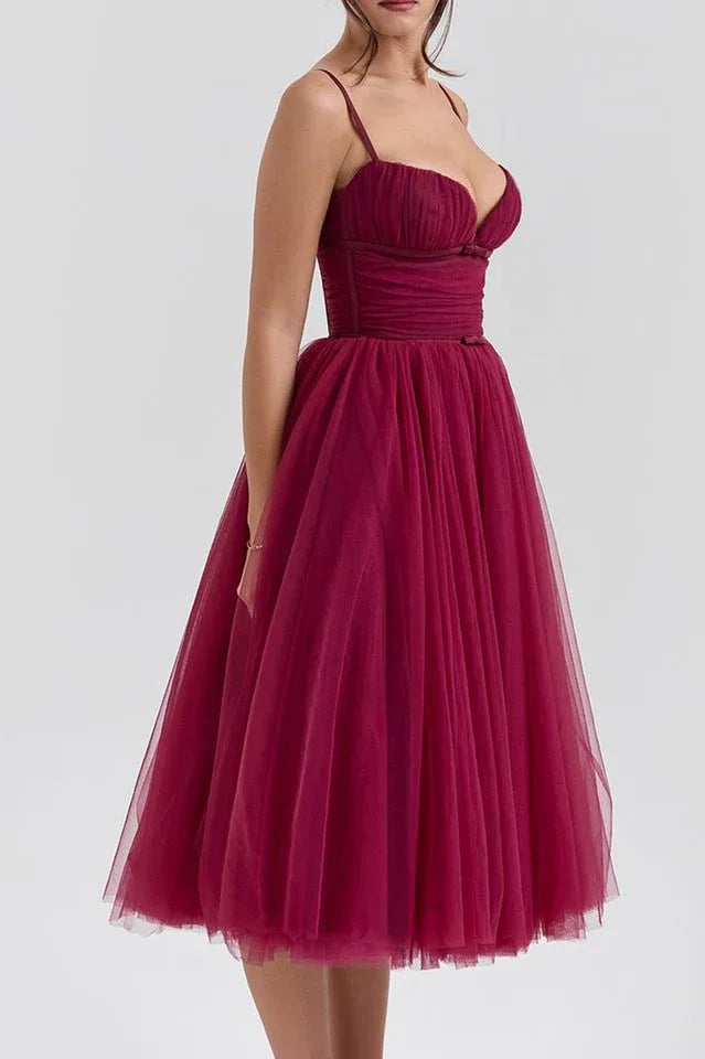 Side view of a woman in a burgundy formal dress with a voluminous tulle skirt.