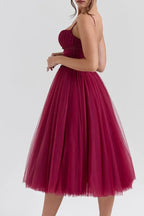 Back view of a woman in a burgundy tea-length dress with a zipper closure.
