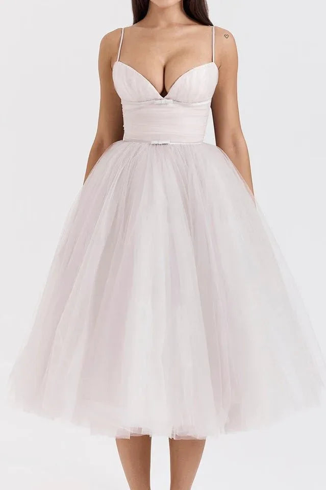 Woman wearing a white tulle tea-length dress with a sweetheart neckline and ruched bodice.