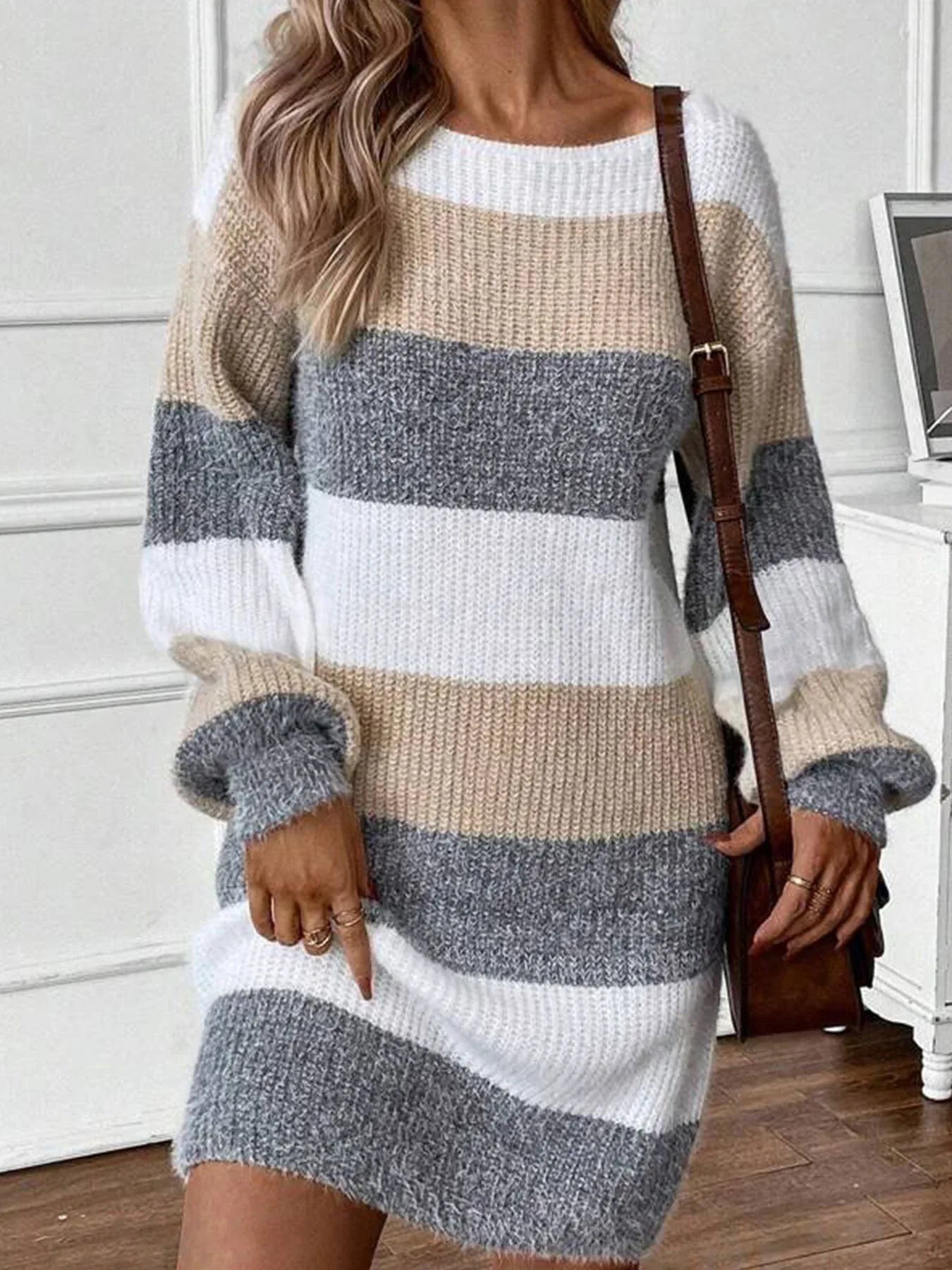 Woman wearing a long-sleeved, striped knit dress with a brown crossbody bag.