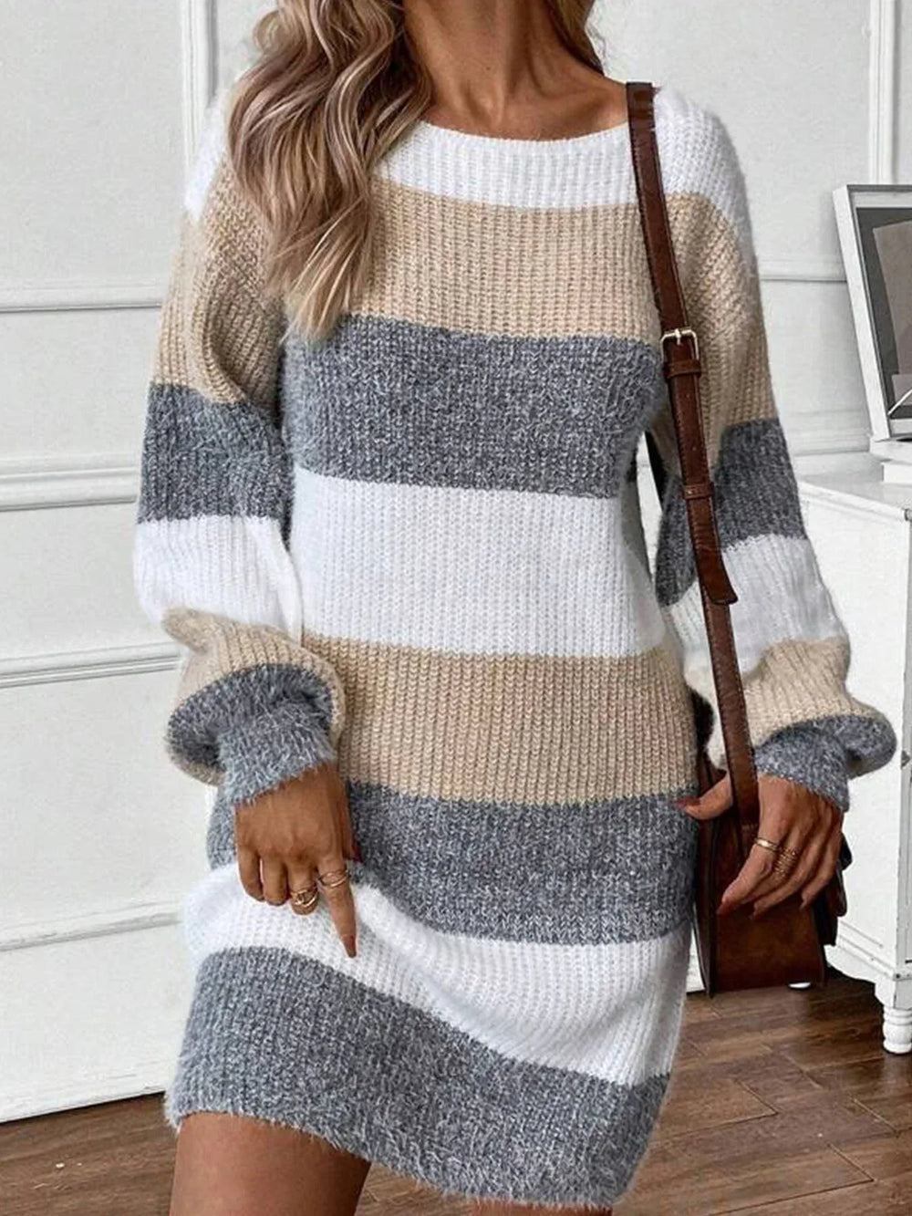 Woman wearing a long-sleeved, striped knit dress with a brown crossbody bag.