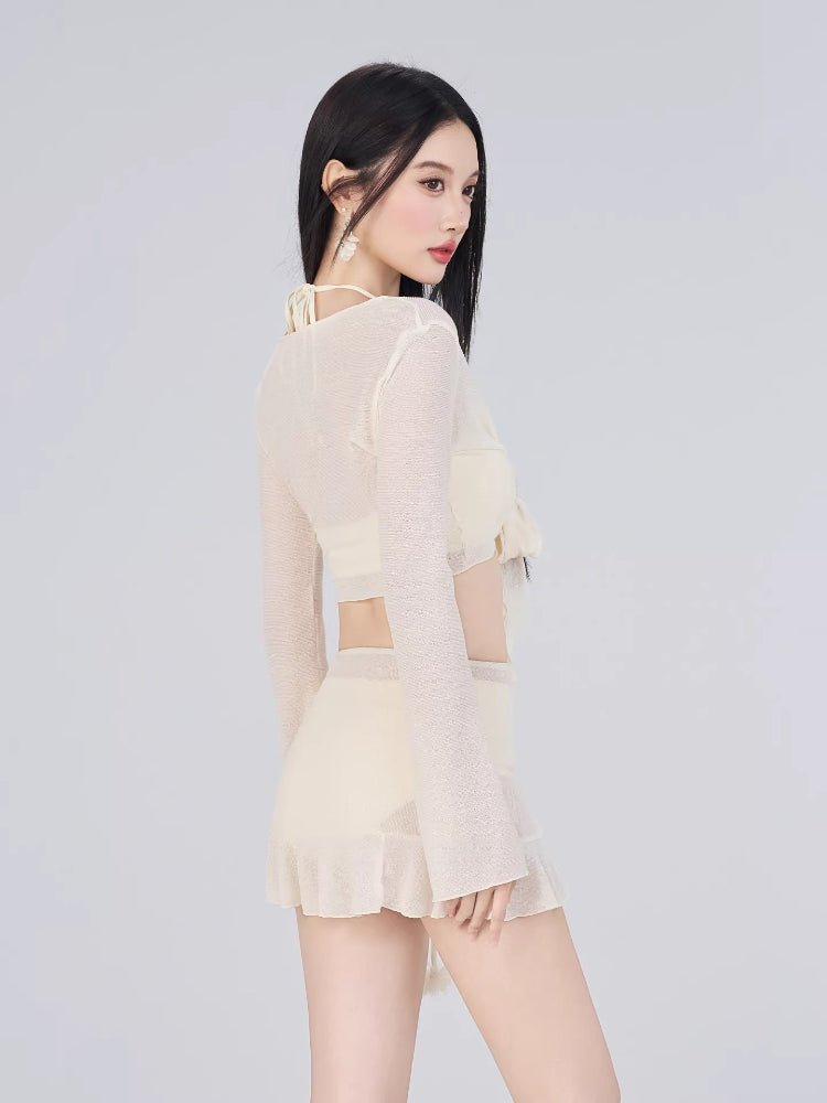 Side profile of a woman wearing a cream-colored bikini set with a sheer cover-up and ruffled hem shorts.