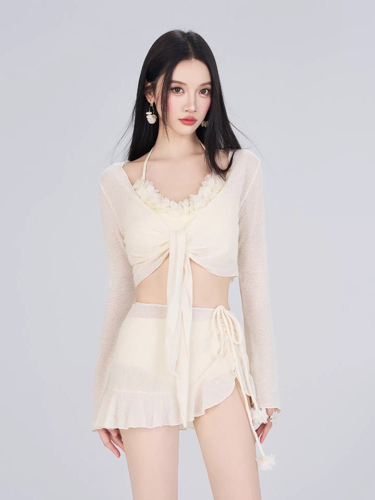 Woman wearing a cream-colored bikini set with a sheer long-sleeved cover-up tied at the front, paired with ruffled hem shorts. Main image