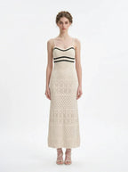 Woman wearing a cream knit maxi dress with black stripes on the bust, shown front view on a white background.