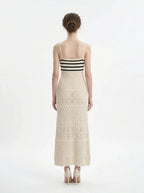 Woman wearing a cream knit maxi dress with black stripes on the bust, shown back view on a white background.