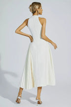 Rear view of a woman wearing a white halter neck midi dress with a keyhole cutout and a pleated skirt panel.