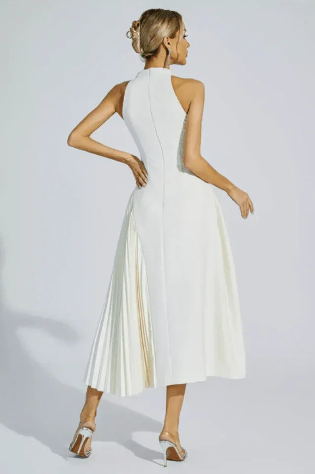 Rear view of a woman wearing a white halter neck midi dress with a keyhole cutout and a pleated skirt panel.