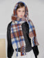 Model wearing a plaid scarf draped over a black jacket and grey sweater.