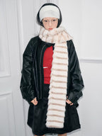 Close-up of a model wearing a cream and brown striped faux fur scarf and a white ribbed headband.