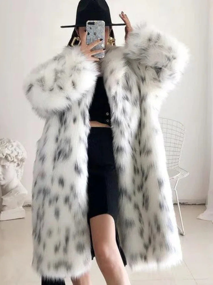 A person wearing a long, white and black spotted faux fur coat, black hat, and black dress, holding a phone to take a mirror selfie. Main image