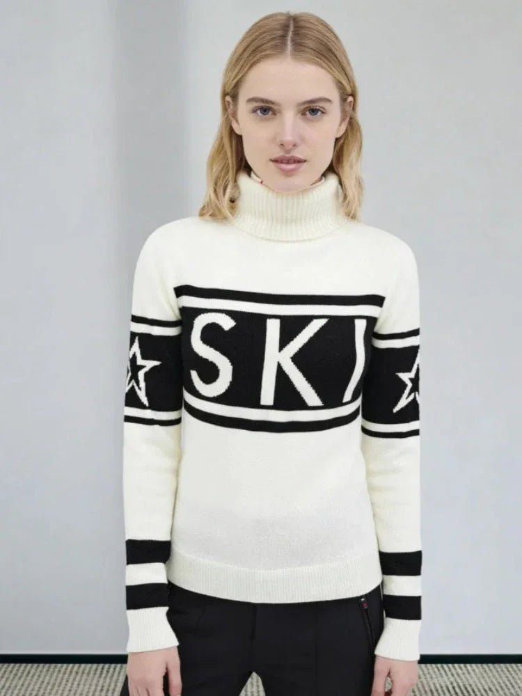 Woman wearing a white and black turtleneck ski sweater with "SKI" graphic and stars on the sleeves.