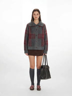 Model wearing a grey plaid knit jacket with a brown mini skirt and grey knee-high socks.