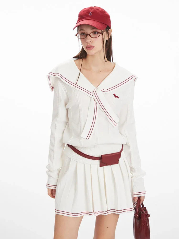 Close-up of a model wearing a white knit sweater with a sailor collar and red trim, red belt bag, and glasses.